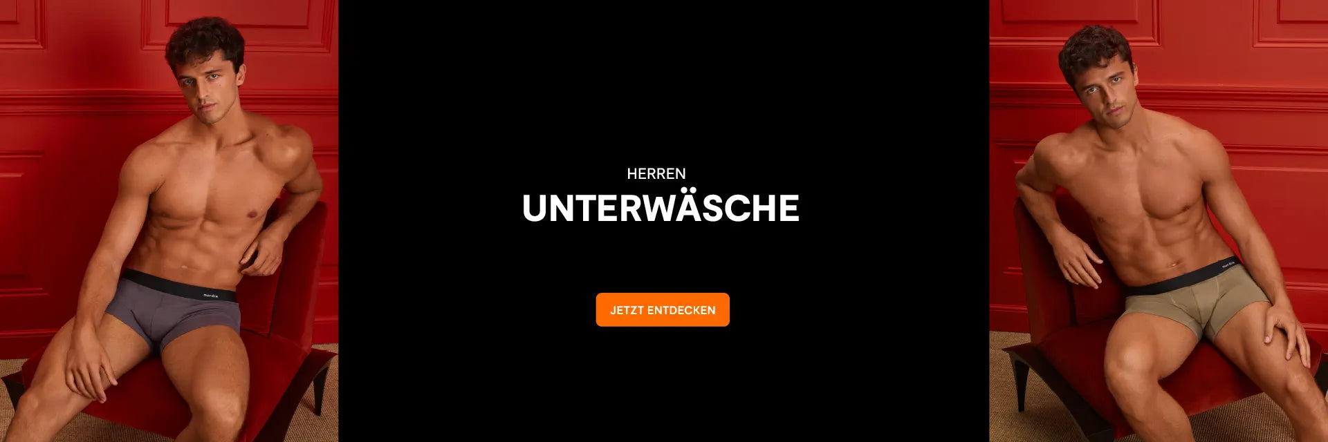 Zwei muskulöse Männer sitzen in Unterwäsche vor rotem Hintergrund, dazwischen schwarzer Bereich mit weißer Schrift 'HERREN UNTERWÄSCHE' und orangefarbenem Button 'JETZT ENTDECKEN'